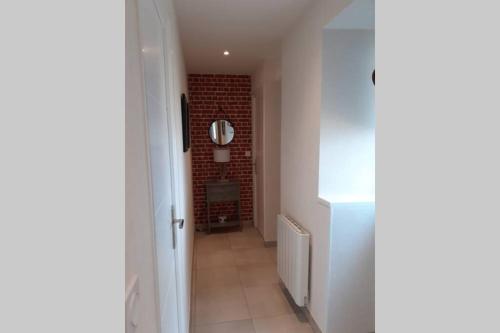 a hallway with a brick wall and a mirror at appartement 4 pers dans longère à 800m de la plage in Plouhinec