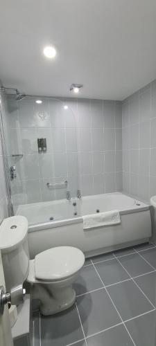 a white bathroom with a toilet and a bath tub at McInnes House rooms with breakfast in Kingussie