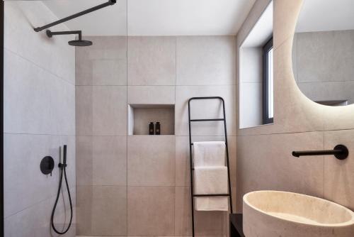 a bathroom with a shower with a tub and a sink at Brilliance Suites in Imerovigli