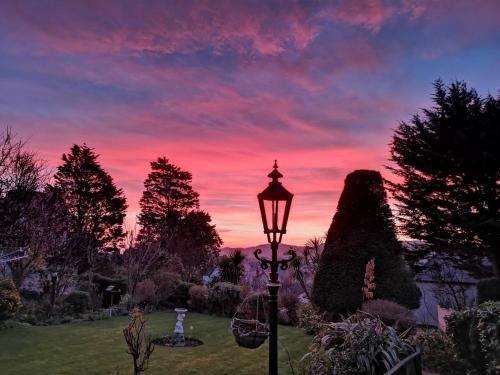a street light in a garden with a sunset at Bron Orme Private Hotel in Llandudno