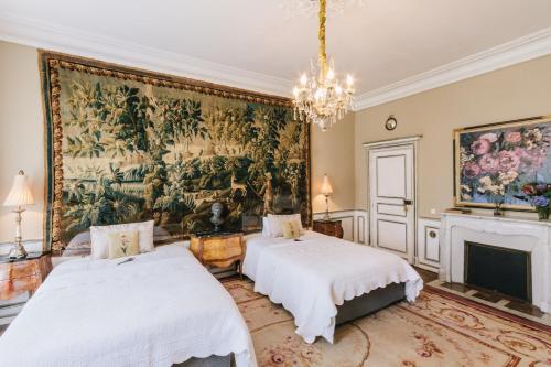 BoussacにあるChâteau La Creuzetteの壁に絵画が飾られた部屋のベッド2台