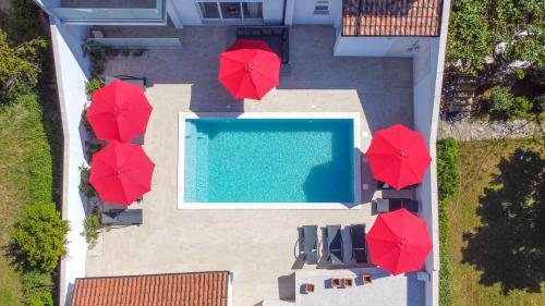 an overhead view of a swimming pool with red umbrellas at Relaxing villa Mala vala in Fažana