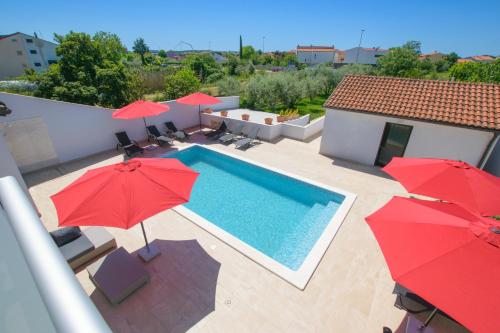 an overhead view of a swimming pool with red umbrellas at Relaxing villa Mala vala in Fažana