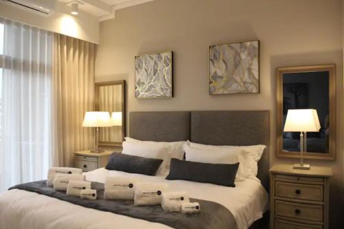 a bedroom with a large bed with two lamps and pillows at Furnished, 1-bedroom, luxury apartment in Menlyn Maine in Pretoria