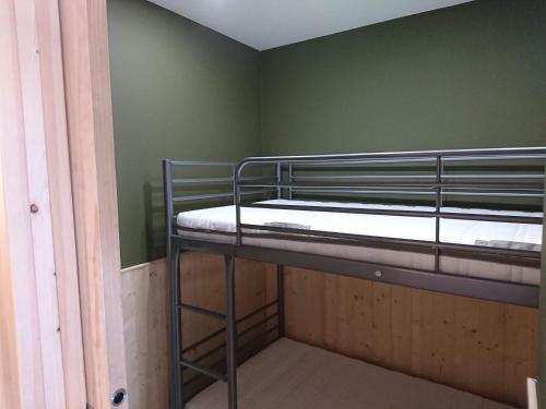 Ce lit superposé se trouve dans un dortoir aux murs verts. dans l'établissement La Croisette, à Mont-de-Lans