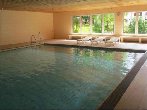 a large swimming pool with white chairs in a room at Ferienwohnung Oberallgäu Ferienpark mit Schwimmbad in Missen-Wilhams