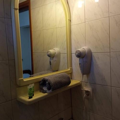 a bathroom with a mirror and a hair dryer on a shelf at Lydia Rooms in Therma