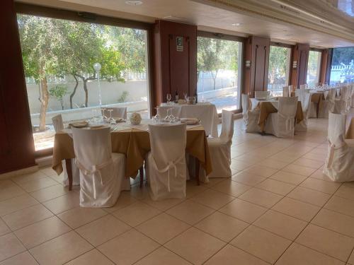 a banquet hall with white tables and white chairs at Hotel Il Melograno in Mattinata