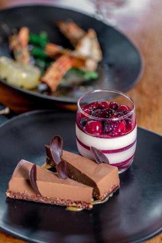 a black plate with a dessert and a glass of cherries at JW Marriott Phuket Resort and Spa in Mai Khao Beach