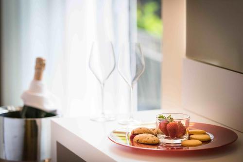 a plate of cookies and strawberries on a counter with a bottle of wine at Enjoy Garda Hotel in Peschiera del Garda