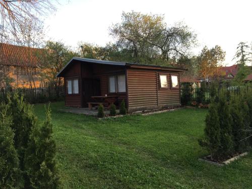 a small wooden cabin in a yard with grass at Dom Pod Długim Wiosłem in Wiartel