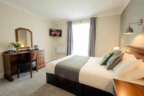 a bedroom with a bed and a desk and a mirror at Hillgrove Guesthouse in Dingle