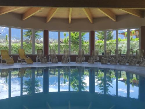 a room with a pool with chairs and windows at Aktiv-Hotel Traube am Mieminger Sonnenplateau in Wildermieming