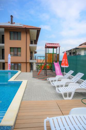 a pool with chairs and a playground next to a building at Вила Влахов in Sapareva Banya