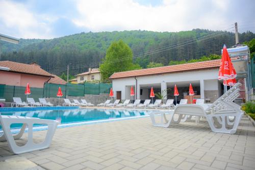 a pool with chairs and umbrellas next to a building at Вила Влахов in Sapareva Banya