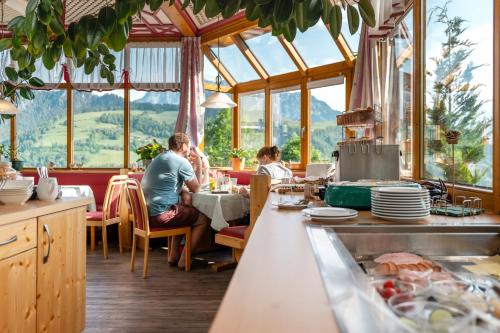 a group of people sitting at a table in a restaurant at Panoramahotel Stocker in Pruggern