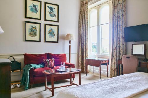 a living room with a red couch and a table at The Bath Priory - A Relais & Chateaux Hotel in Bath