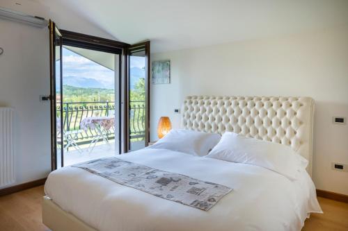 a bedroom with a large white bed and a balcony at Agriturismo Contessi in San Daniele del Friuli