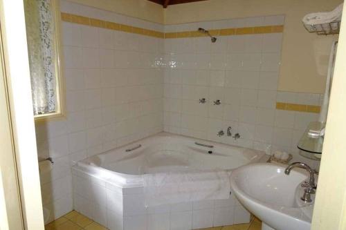 Baño blanco con bañera y lavamanos en Karinya "Peaceful Home", en Bandon Grove