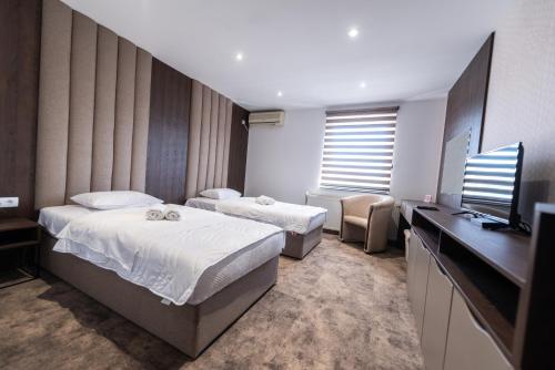 a hotel room with two beds and a flat screen tv at Hotel Stari Krovovi in Novi Sad