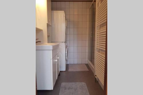 a small kitchen with white appliances and white tiles at De Blauwe Reiger mooi dubbel chalet in de Veluwse bossen in Putten