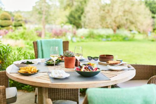 a wooden table with plates of food and glasses of wine at The Bath Priory - A Relais & Chateaux Hotel in Bath