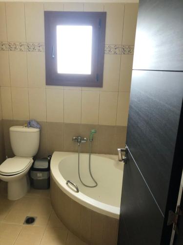 a bathroom with a tub and a toilet and a window at 1 Bed Flat - Sleeps 4 - Garden - Parking - Wifi in Mouzákion