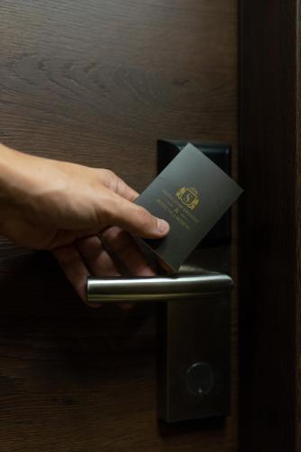 a person holding a passport on a door handle at Hotel Stari Krovovi in Novi Sad
