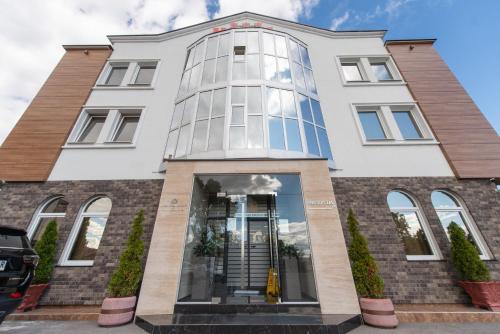 a large white building with a glass facade at Hotel Stari Krovovi in Novi Sad