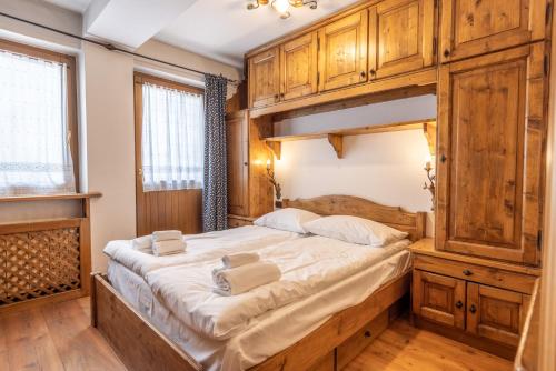 - une chambre avec un grand lit et des placards en bois dans l'établissement Casa Cristallo, à Cortina dʼAmpezzo