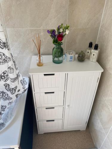 a white cabinet with a vase of flowers on it at Amber Guest House in London