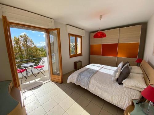 1 dormitorio con 1 cama y balcón con mesa en Villa Bianca, en Villa Celiera