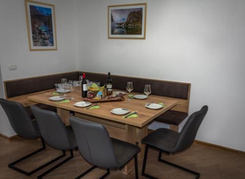 a wooden table with chairs and a bottle of wine at Hiša Bohinc z wellnessom in Tolmin