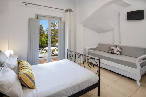 a bedroom with a bed and a couch and a balcony at Villa Soula in Fira
