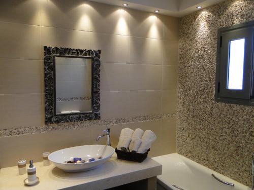 y baño con lavabo, espejo y bañera. en Porto Heli Villas & Studios, en Porto Heli