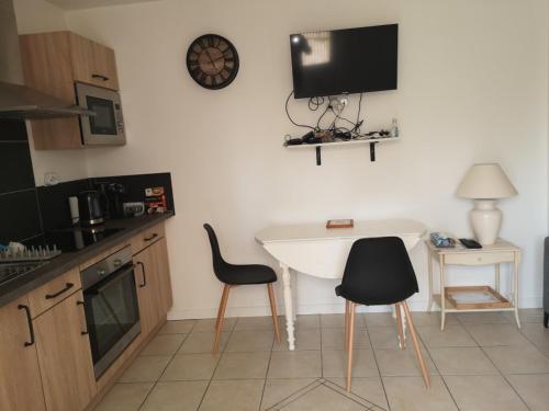 a kitchen with a white table and two chairs at Appartement 2 pièces avec terrasse proche mer et commerces in Ouistreham