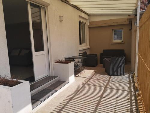 a patio with a table and chairs on a house at Appartement 2 pièces avec terrasse proche mer et commerces in Ouistreham