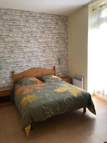 un letto in una camera da letto con muro di mattoni di T2 résidence Grand Hotel appt 102 - village thermal montagne ad Aulus-les-Bains