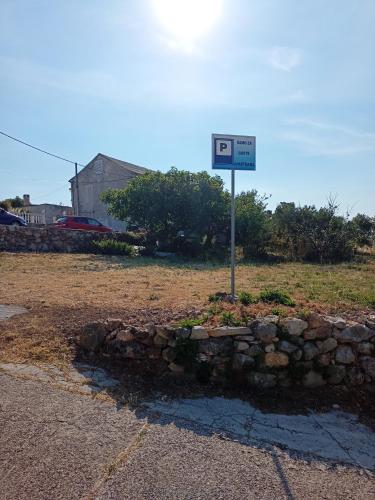 a street sign in a field with a stone wall at Apartments Ruža Dragove Dugi otok in Dragove