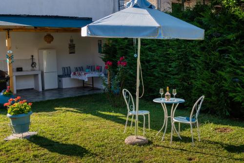 a table and chairs under an umbrella in a yard at Athena's Studios in Polykhrono