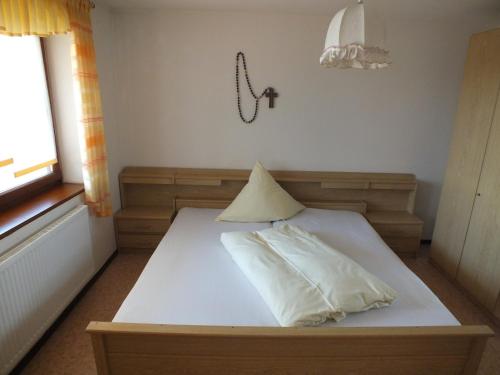 Una cama blanca con una almohada encima. en Pension & Reitschule Fuchsenhof, en Seebarn