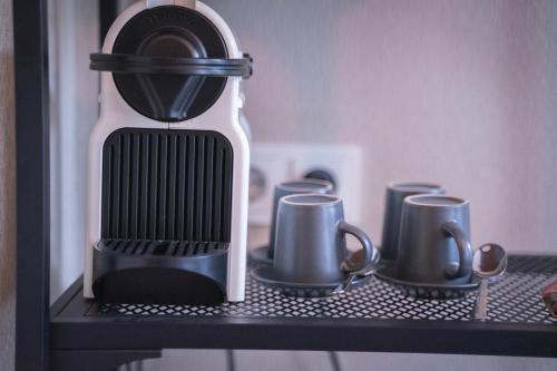 a coffee maker on a shelf with cups on it at Hotel Vondel Garden City Centre in Amsterdam