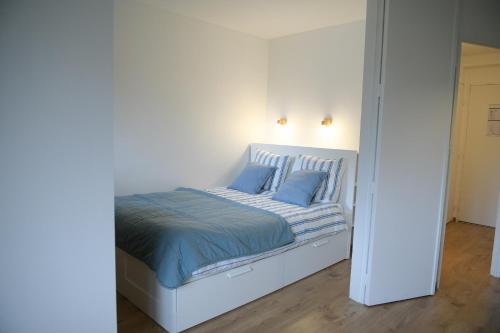 uma cama branca com almofadas azuis num quarto em Appartement Cosy - Aiguille du Midi em Chamonix-Mont-Blanc