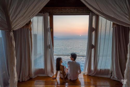 un hombre y una mujer mirando por una ventana al océano en Santhiya Koh Yao Yai Resort & Spa - Compulsory Join Santhiya Speedboat from-to Ao Po Grand Marina at Phuket, en Ko Yao Yai