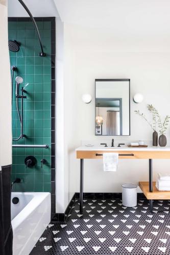 a bathroom with green tiles and a sink and a tub at El Capitan Hotel in Merced