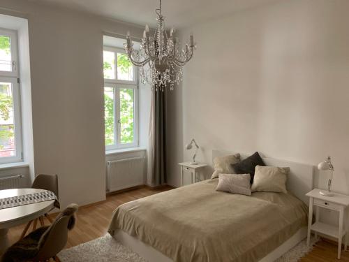 a white bedroom with a bed and a chandelier at LieblingsPlatz in Vienna