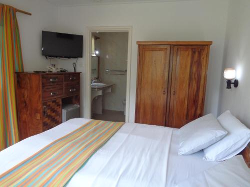 a bedroom with a bed and a dresser and a television at Chez Michellin Pensions Residence in La Digue