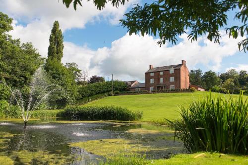 a house and a pond in front of a house at Bettws Hall Accommodation in Newtown