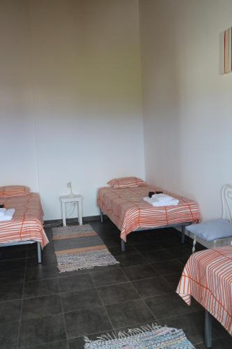 Zimmer mit 2 Betten und 2 Tischen mit Teppichen in der Unterkunft Casa das Camarinhas RAAL 542- casa partilhada in Ginetes