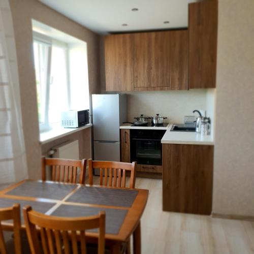 uma cozinha com uma mesa e cadeiras e um frigorífico em ashlife_home em Liepāja